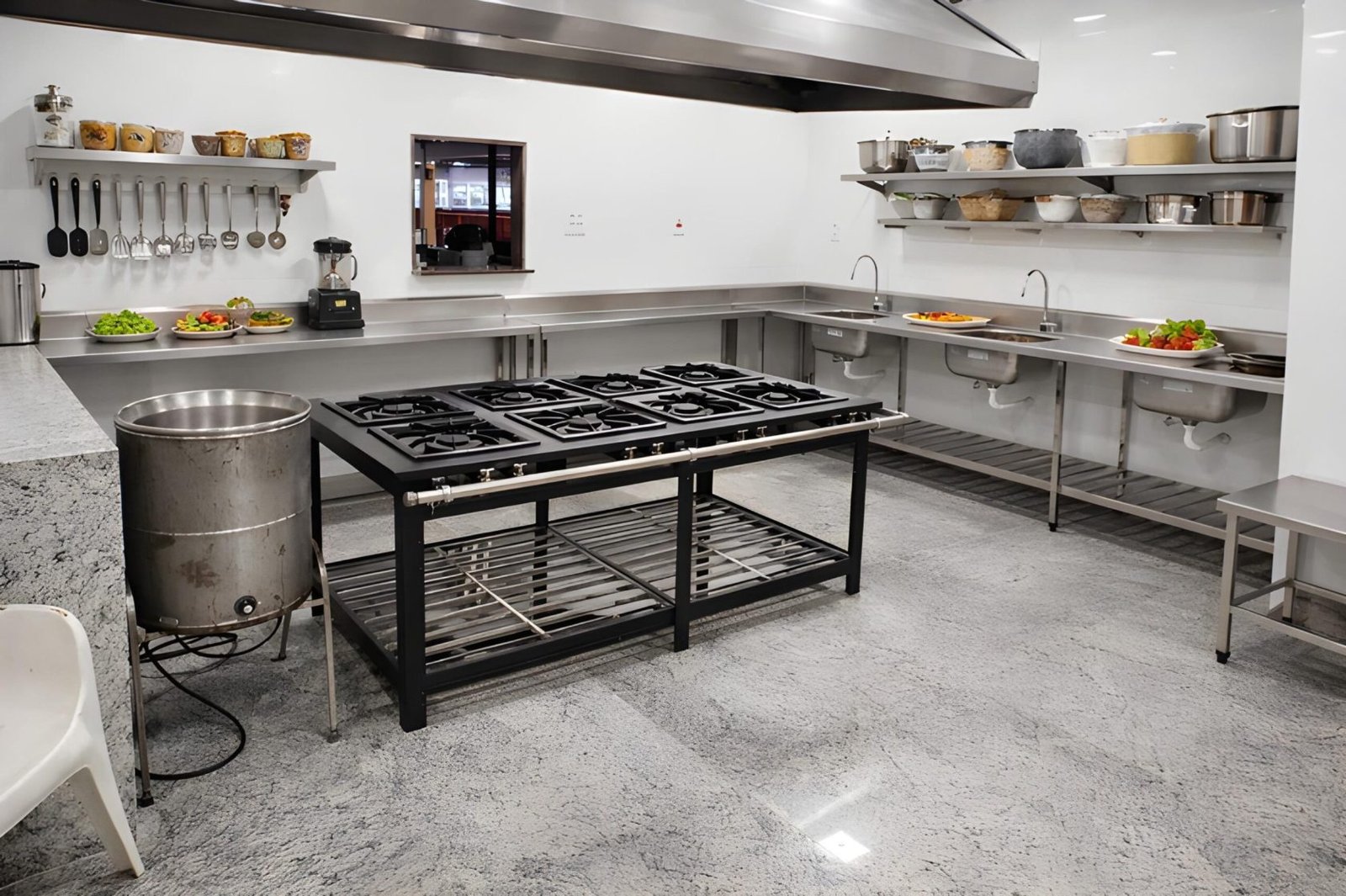 Cozinha industrial com bancadas, pia e prateleiras em aço inox